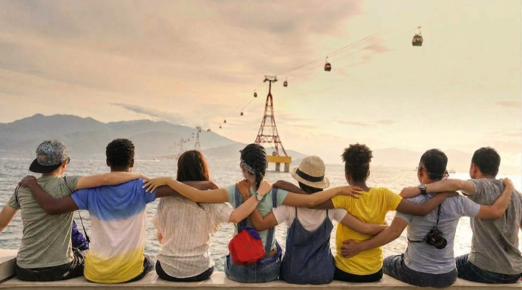 Eight friends of different backgrounds sitting together with their arms around each other